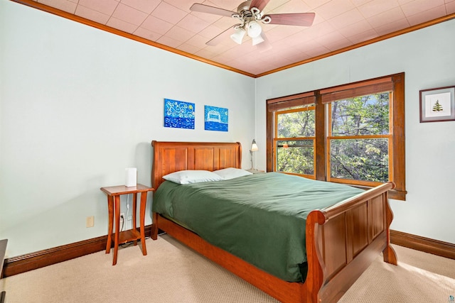 carpeted bedroom with a ceiling fan, baseboards, and ornamental molding