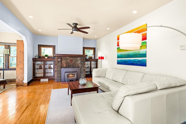 living room featuring a ceiling fan, visible vents, light wood finished floors, a fireplace with flush hearth, and recessed lighting