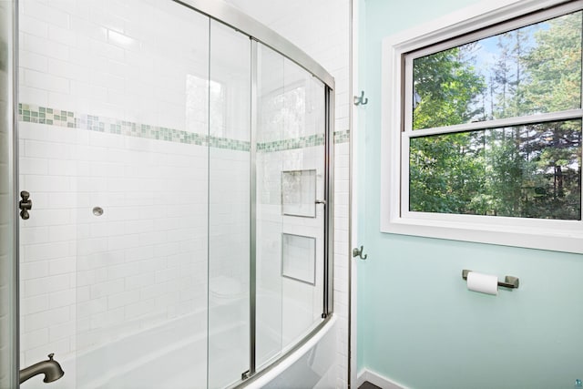 full bathroom with baseboards and bath / shower combo with glass door