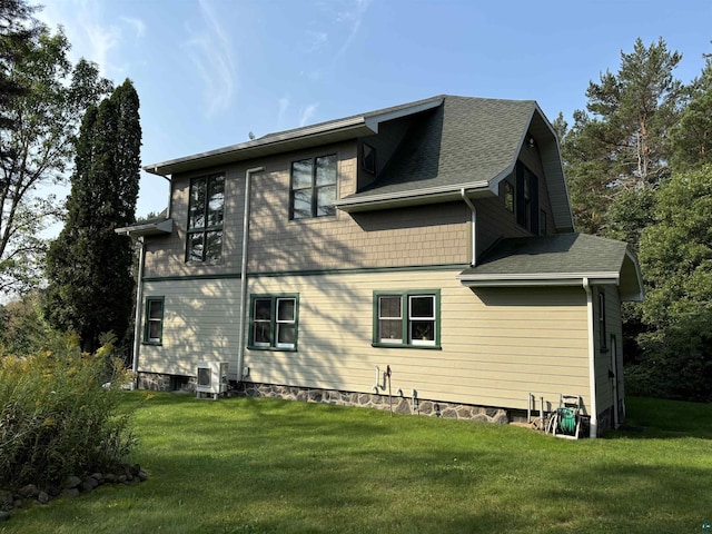 rear view of property featuring a yard, roof with shingles, and central AC unit