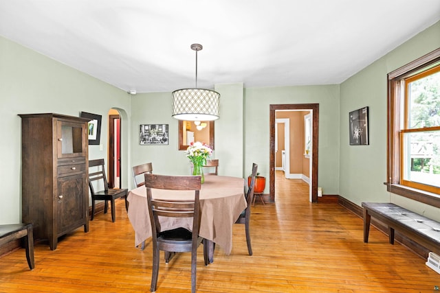 dining room with arched walkways, visible vents, light wood-type flooring, and baseboards