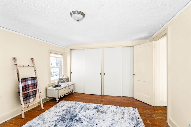 bedroom featuring a closet, a textured ceiling, baseboards, and wood finished floors