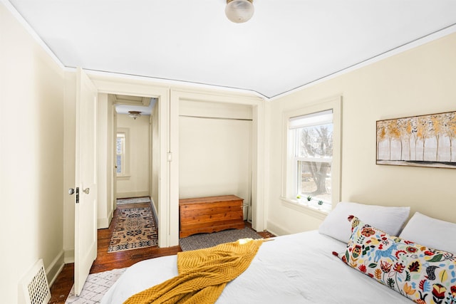 bedroom with visible vents, baseboards, a closet, and wood finished floors