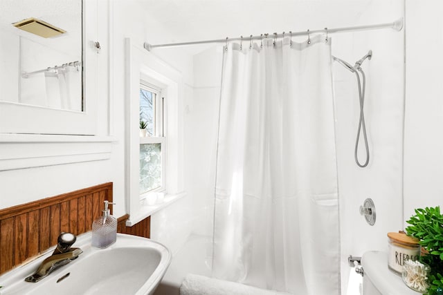 bathroom with a sink, shower / bathtub combination with curtain, and toilet