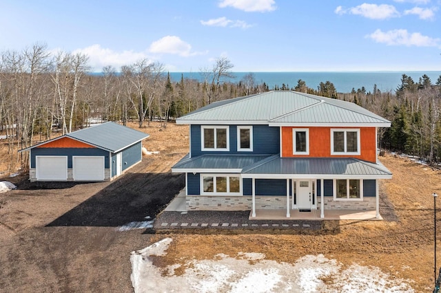 view of front of house with a water view, an outbuilding, stone siding, metal roof, and a garage