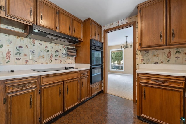 kitchen with under cabinet range hood, brown cabinets, black appliances, and light countertops