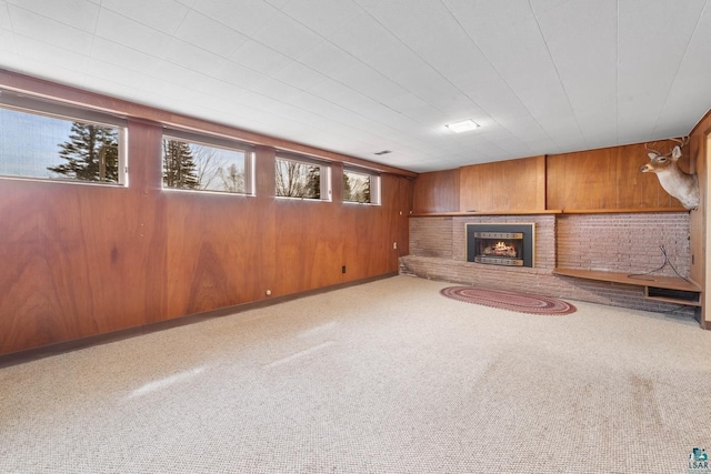 unfurnished living room featuring carpet flooring, wood walls, and a fireplace