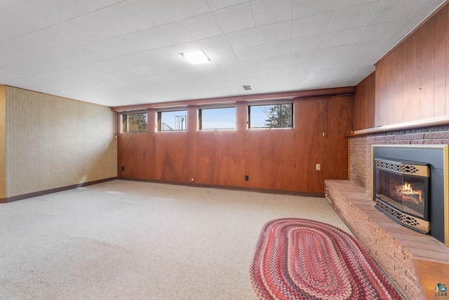 unfurnished living room with light carpet, wood walls, a fireplace, and baseboards