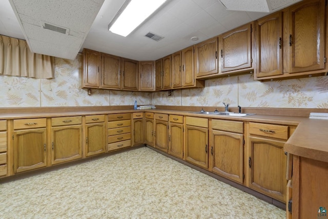 kitchen with a sink, brown cabinets, and wallpapered walls