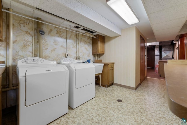 laundry area with wallpapered walls, cabinet space, washing machine and dryer, and light floors