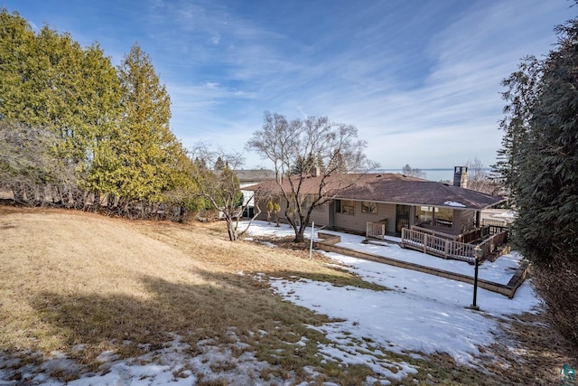 snow covered rear of property featuring a deck and dirt driveway