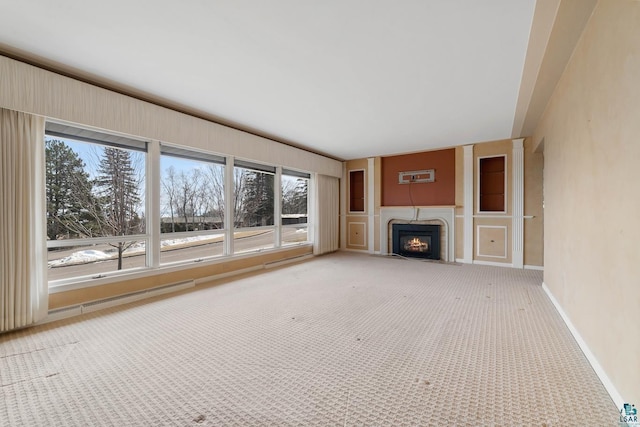 unfurnished living room featuring a fireplace with flush hearth, baseboards, and carpet floors