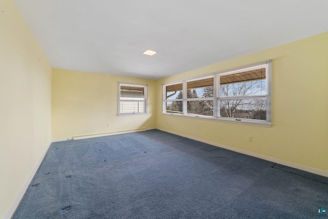 empty room featuring baseboards and dark colored carpet