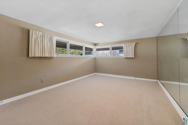 empty room featuring light colored carpet and baseboards