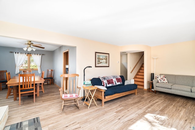 living area featuring ceiling fan, baseboards, stairs, and light wood-style floors