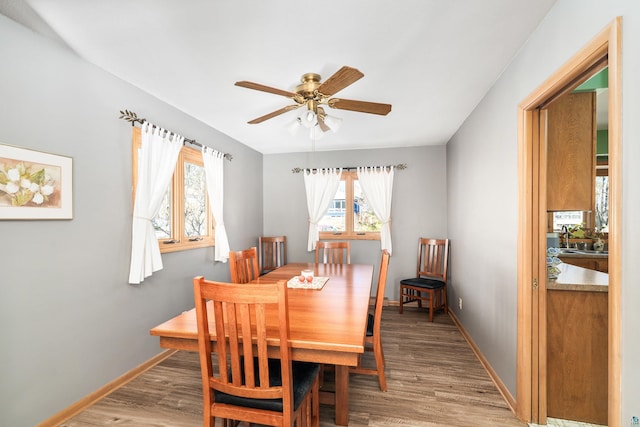 dining room featuring baseboards, light wood-style flooring, and a ceiling fan