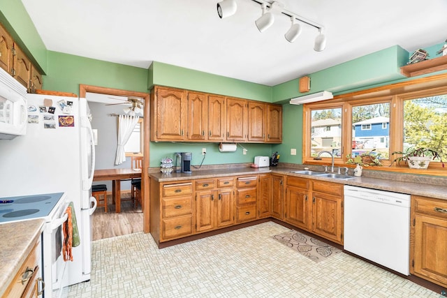 kitchen with white appliances, a ceiling fan, a sink, light countertops, and brown cabinets