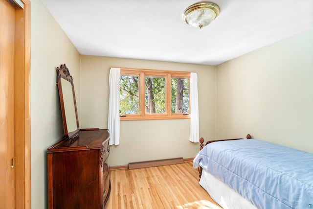 bedroom with baseboards, light wood-type flooring, and a baseboard radiator