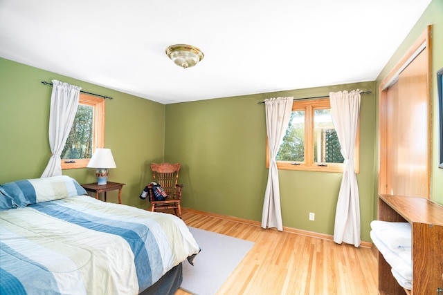 bedroom with multiple windows, baseboards, and wood finished floors