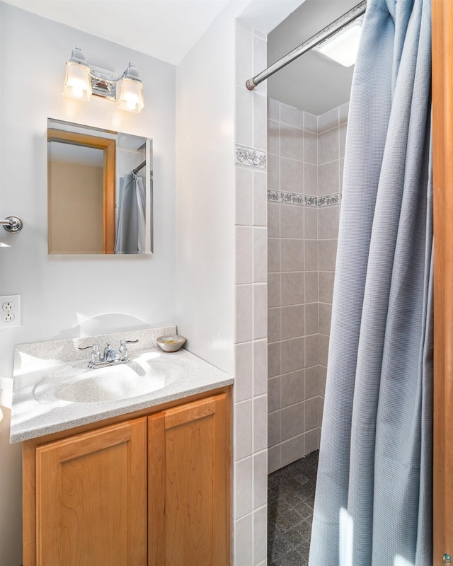 full bath with tiled shower and vanity