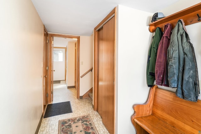 hallway with stairway, baseboards, and light floors