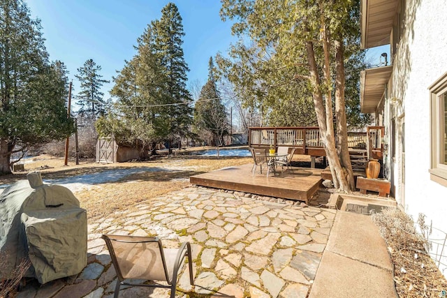 view of patio / terrace featuring a wooden deck, an outbuilding, and a shed