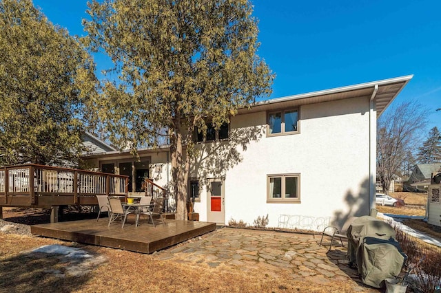 back of property featuring stucco siding, a patio, and a deck