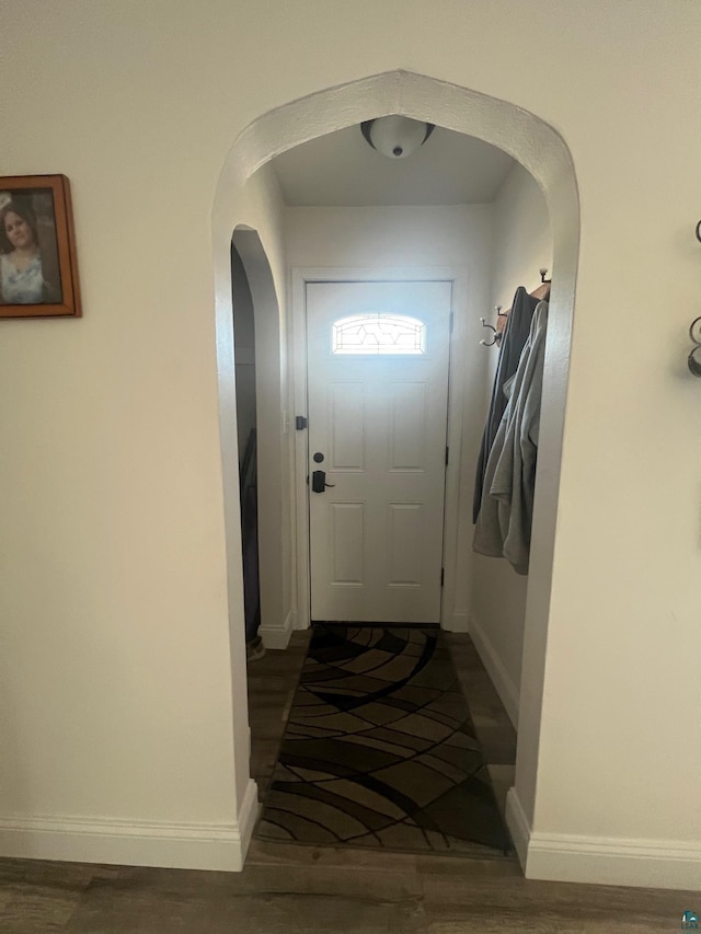 doorway with baseboards, arched walkways, and wood finished floors