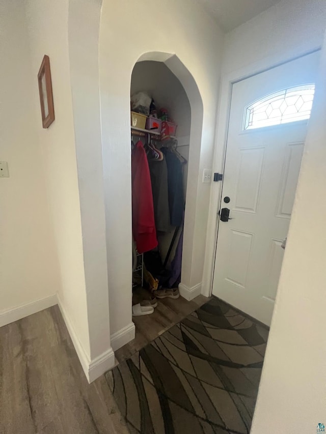 foyer featuring baseboards, arched walkways, and wood finished floors