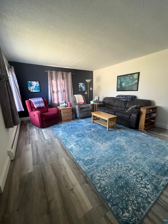 living room with a baseboard heating unit, wood finished floors, baseboards, and a textured ceiling