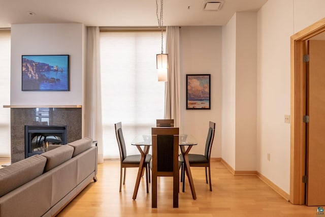 dining room featuring baseboards, visible vents, light wood-type flooring, and a tile fireplace