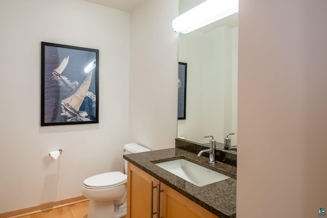 bathroom with baseboards, toilet, wood finished floors, and vanity