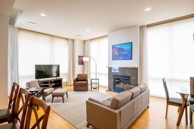 living area featuring visible vents, a tiled fireplace, expansive windows, recessed lighting, and light wood-style floors