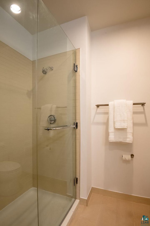 bathroom featuring baseboards, toilet, a stall shower, and tile patterned flooring