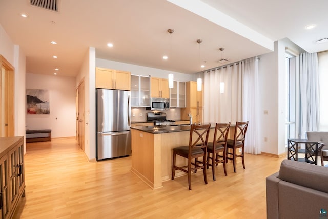 kitchen with a breakfast bar area, light wood-style flooring, visible vents, and appliances with stainless steel finishes