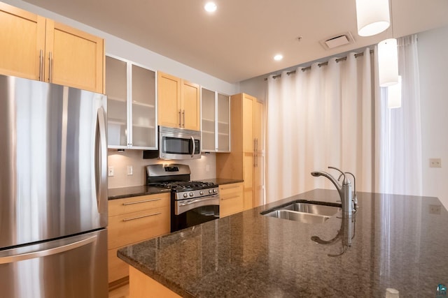 kitchen featuring visible vents, light brown cabinets, a sink, stainless steel appliances, and glass insert cabinets