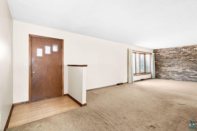 carpeted foyer with baseboards, visible vents, brick wall, a textured ceiling, and tile patterned floors