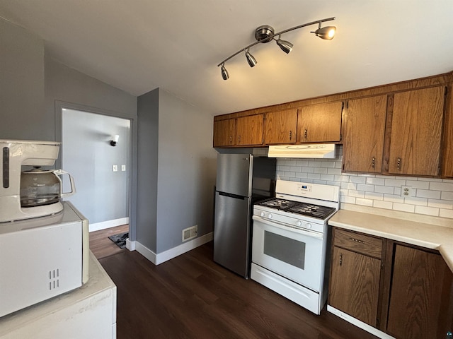 kitchen featuring brown cabinets, white range with gas cooktop, dark wood-style flooring, under cabinet range hood, and tasteful backsplash