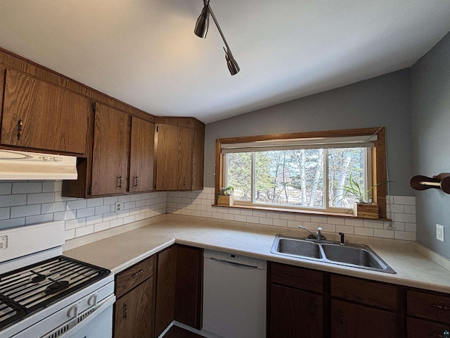 kitchen featuring light countertops, lofted ceiling, range hood, white appliances, and a sink