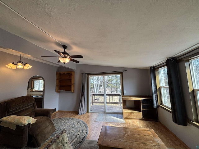 living room featuring a ceiling fan, lofted ceiling, light wood-style flooring, and a healthy amount of sunlight