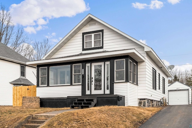 bungalow-style home with fence, entry steps, a garage, an outbuilding, and driveway