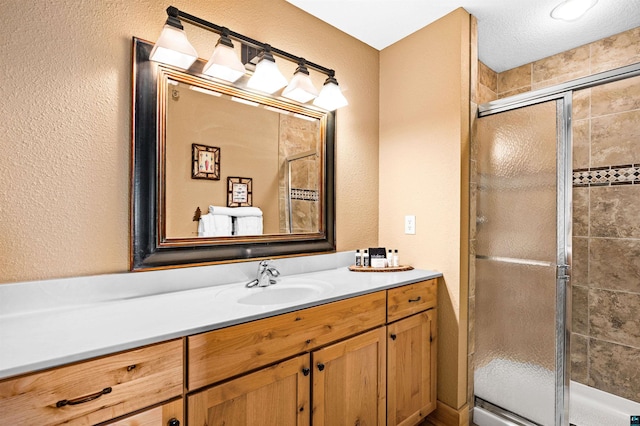 bathroom featuring vanity, a textured wall, and a stall shower