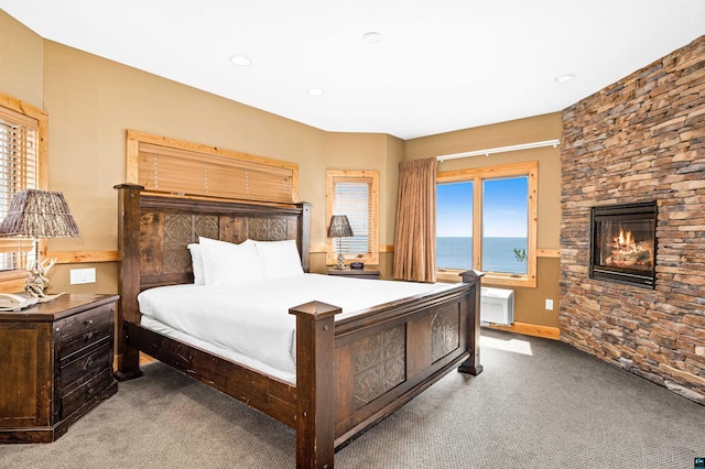 carpeted bedroom with recessed lighting, a water view, and a fireplace