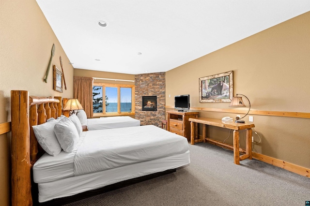 bedroom featuring baseboards, carpet, and a fireplace