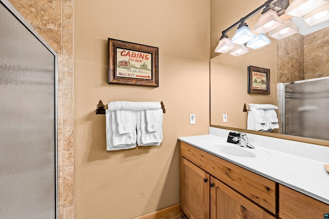 full bath featuring a stall shower, vanity, and a textured wall