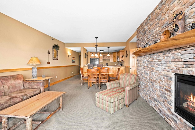 living room featuring a stone fireplace, light colored carpet, and baseboards