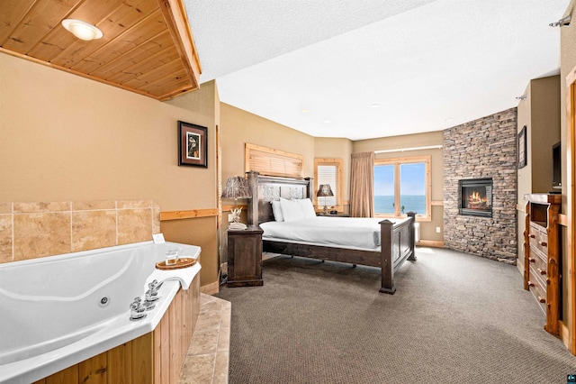 bedroom with a stone fireplace, wood ceiling, and carpet