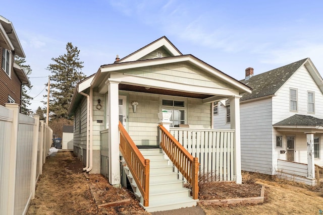 shotgun-style home featuring a porch and fence