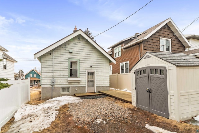 rear view of house with a storage shed, an outdoor structure, and fence