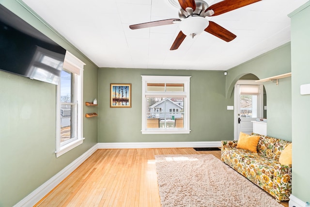 sitting room with baseboards, plenty of natural light, arched walkways, and hardwood / wood-style floors